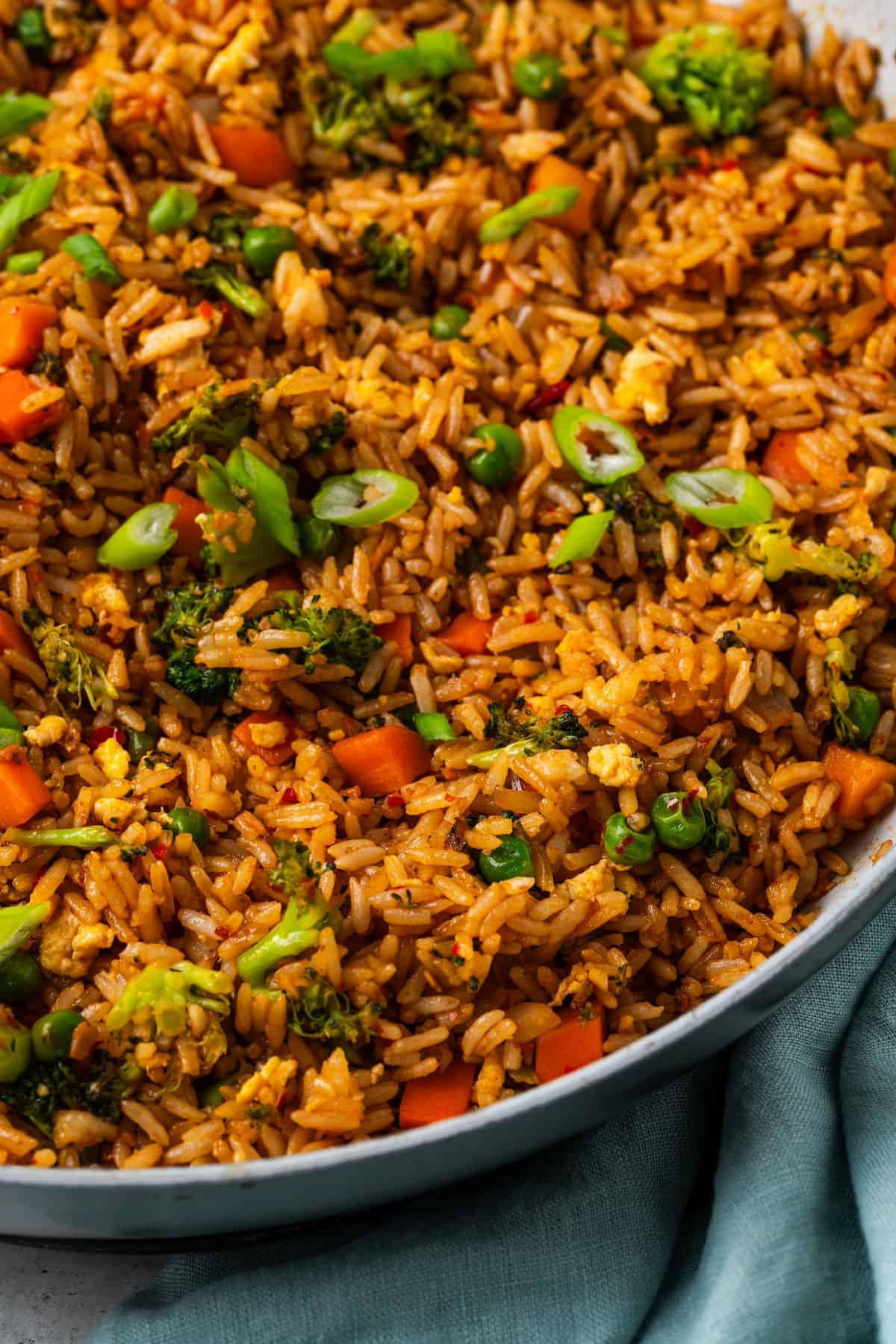 Close up of vegetable fried rice with peas, carrots, broccoli and eggs in a large skillet.