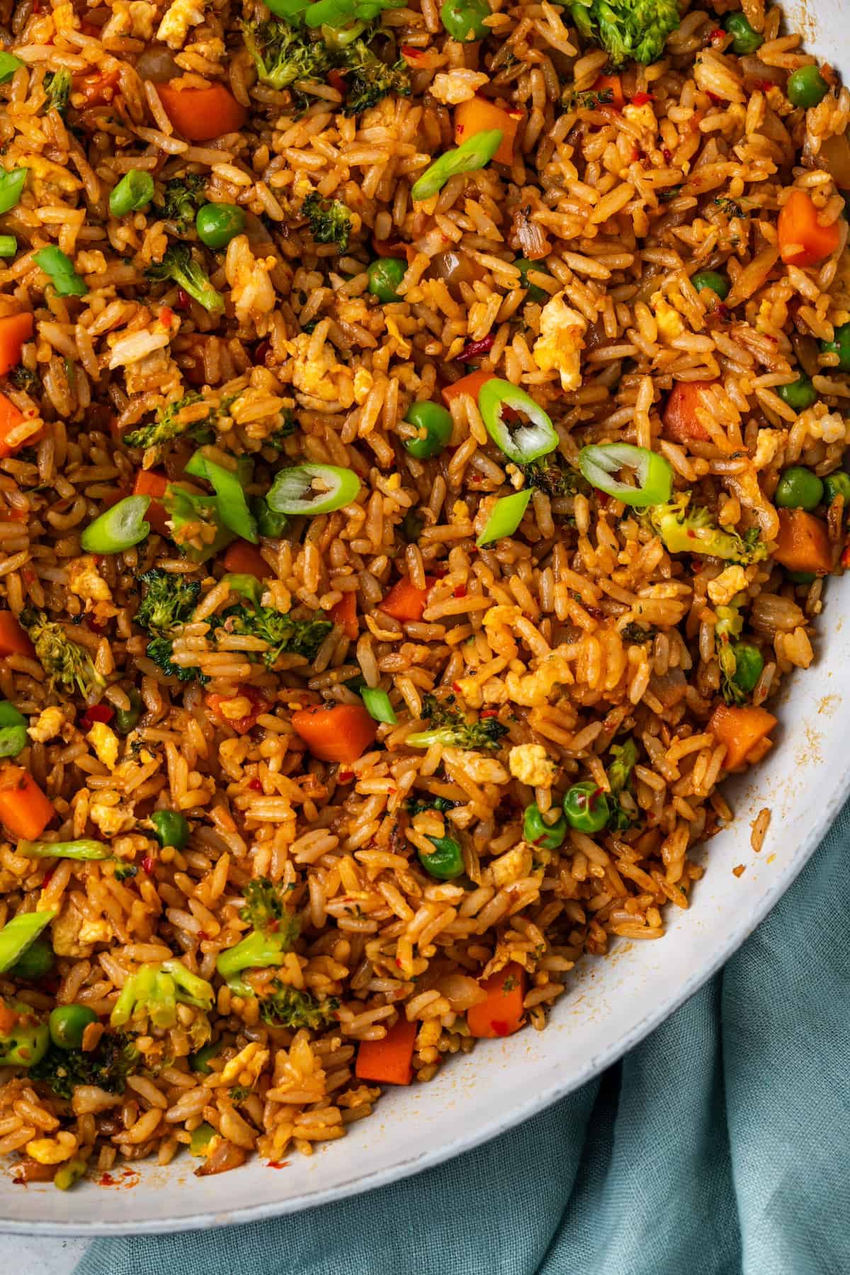 Veggie fried rice in a large skillet with sliced green onions sprinkled on top.