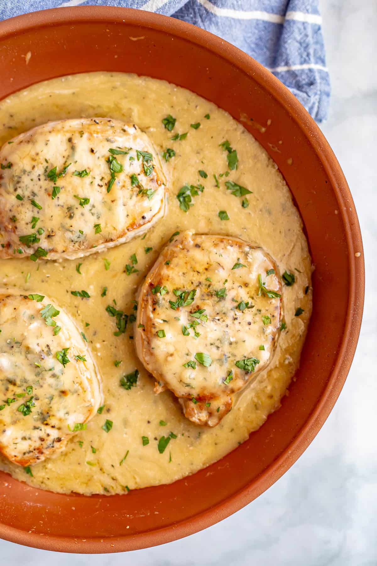 Close up of seared pork chops with gravy in a copper pan.