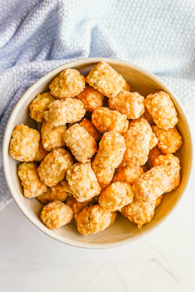 A bowl full of frozen tater tots.