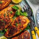 Baked paprika chicken served on a teal platter with fresh parsley and lemon wedges and a text overlay on the photo.