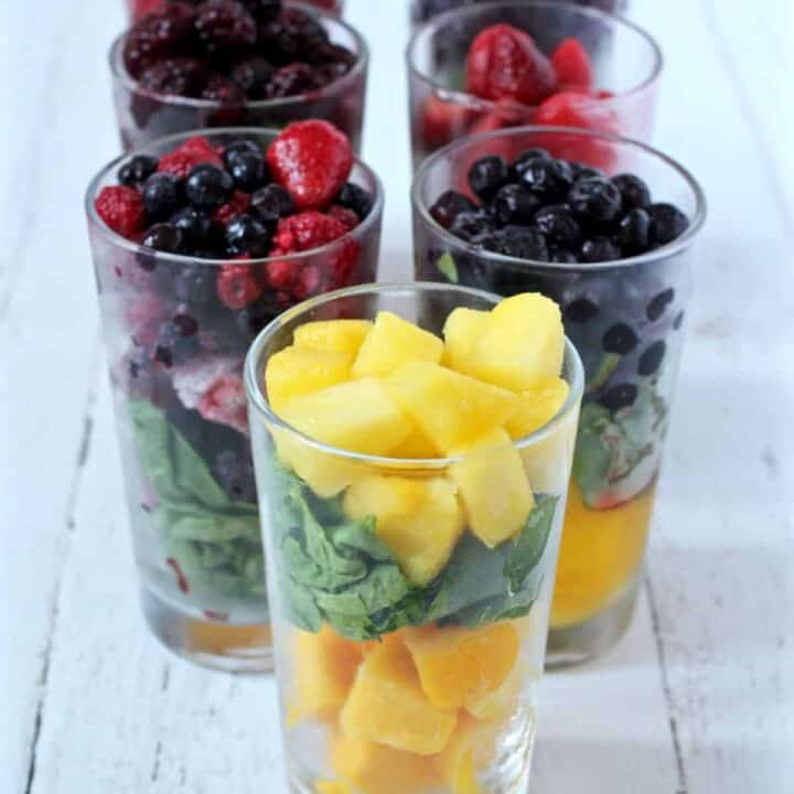 Glasses lined up with different fruit mixes for blending into yogurt.