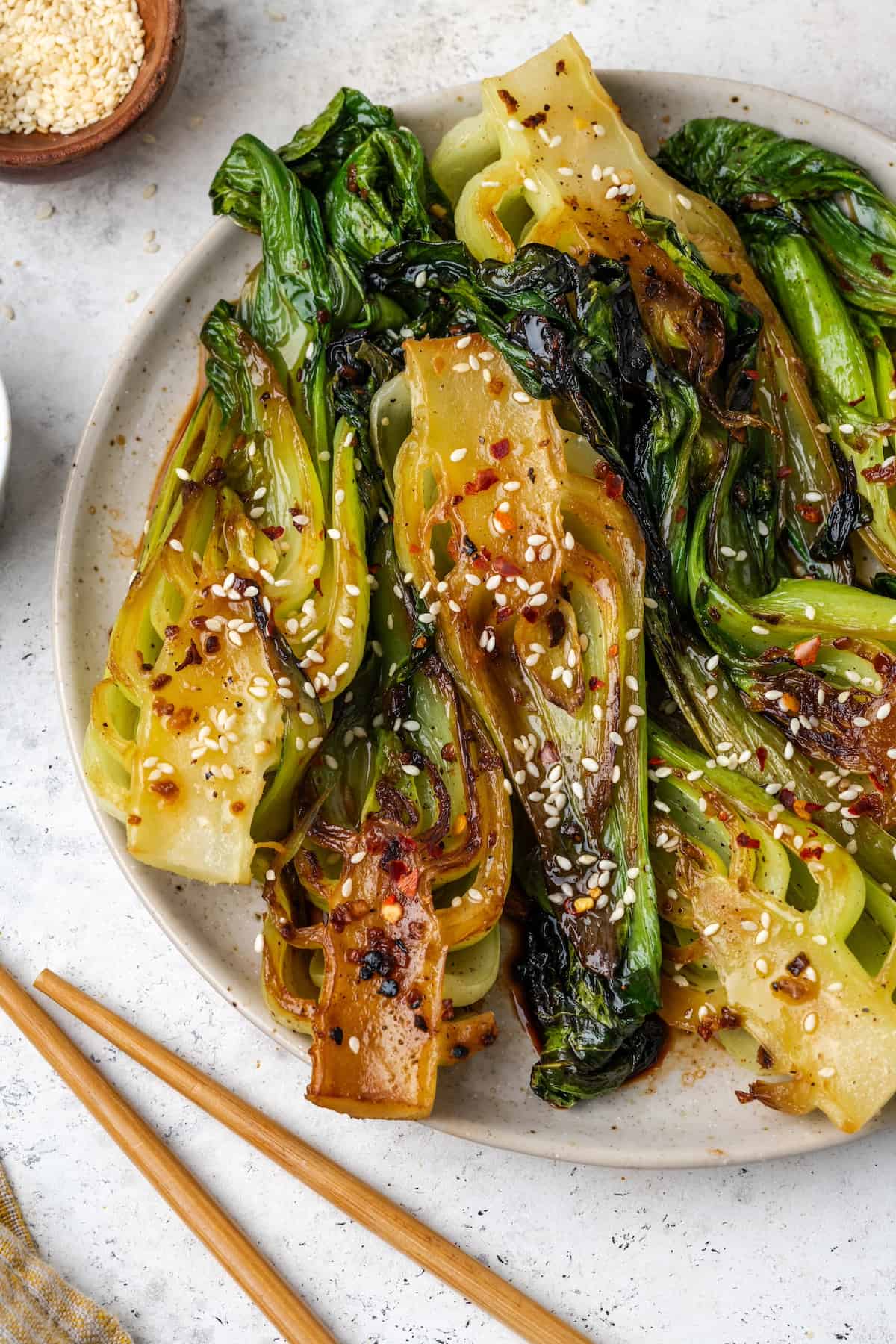 Cooked baby bok choy with soy sauce, sesame seeds and garlic and ginger served on a large round platter.