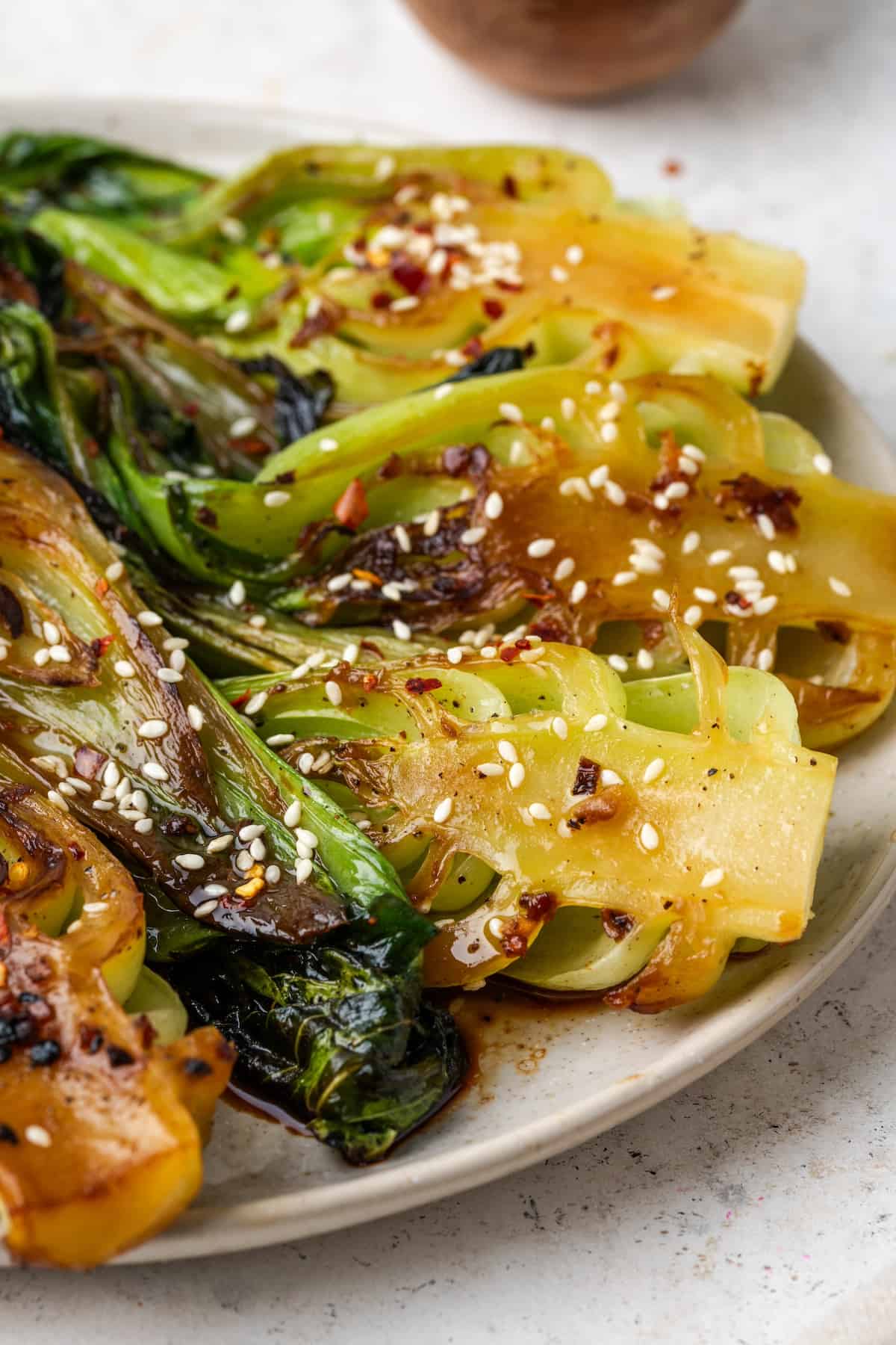 Close up of cooked baby bok choy with soy sauce, sesame seeds and garlic and ginger served on a large round platter.