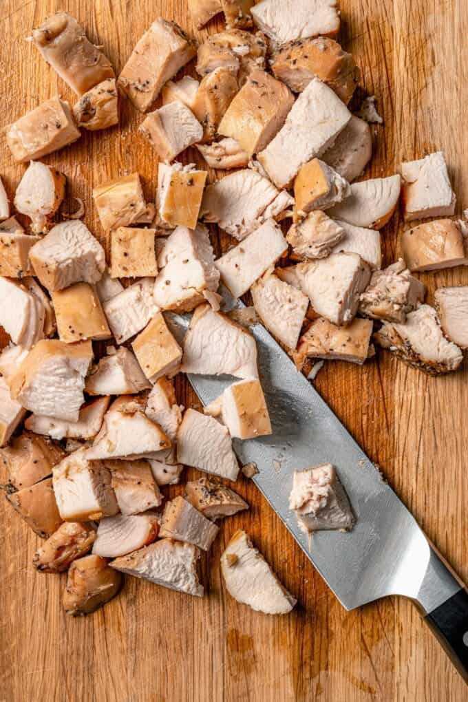 Chopped cooked chicken on a wooden cutting board.