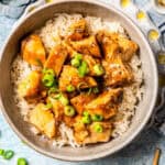 A dinner bowl of rice and a sauce soy bourbon chicken topped with sliced green onions with a text overlay on the photo.