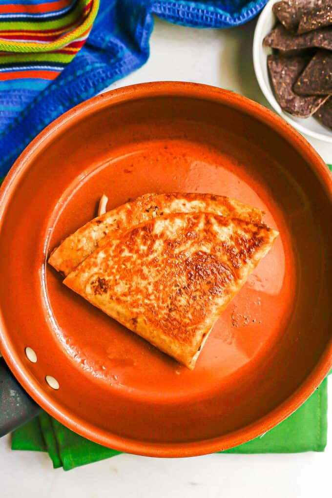 A golden brown fajita folded wrap in a copper pan after being heated.
