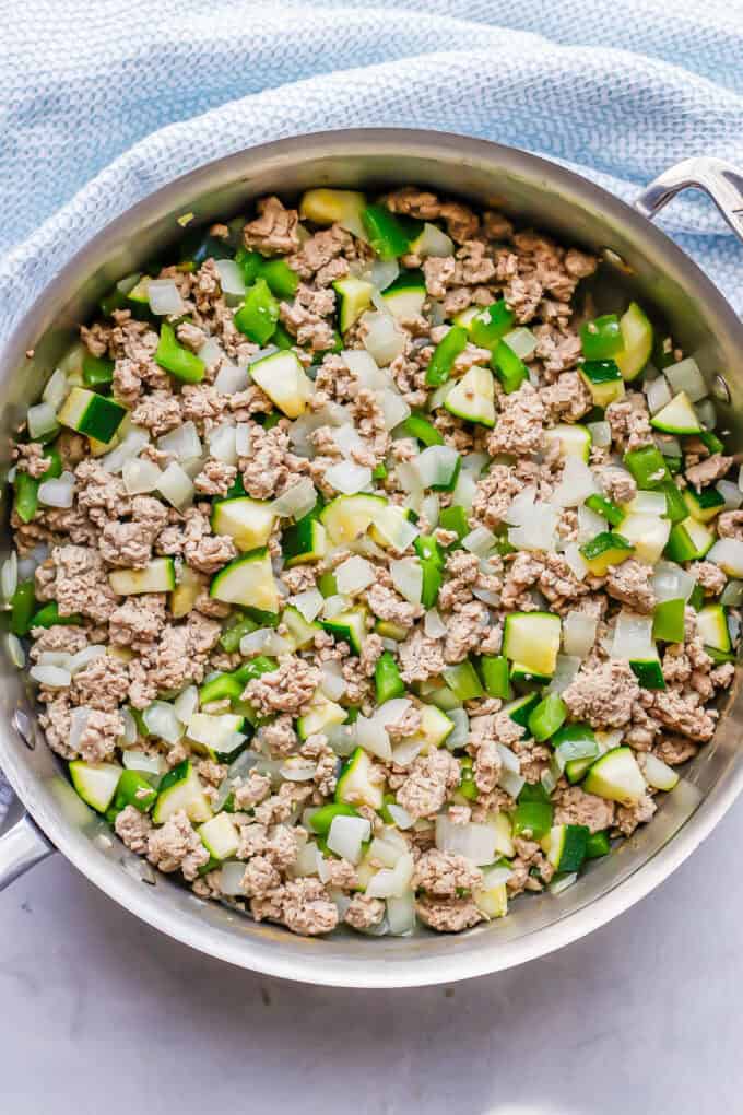 Ground turkey cooked with onions, pepper and zucchini in a large deep skillet.