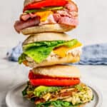 Three different sandwich melts stacked on top of each other on a white plate with a text overlay on the photo.