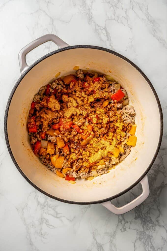Cooked ground turkey with onions, peppers and taco seasoning in a large pot.
