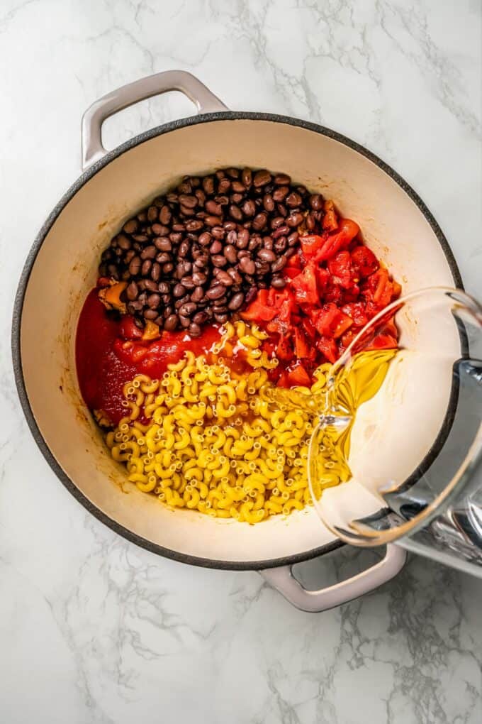 Water being added to a large pot of taco pasta as it's being cooked.