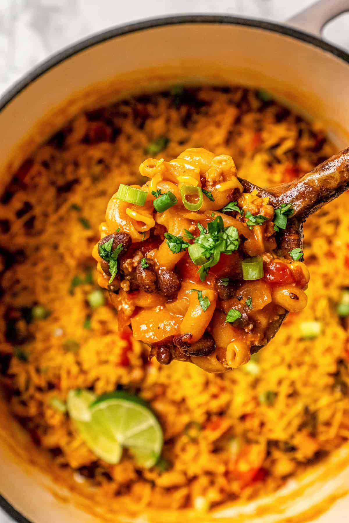 A scoop of taco pasta being lifted from a large pot.