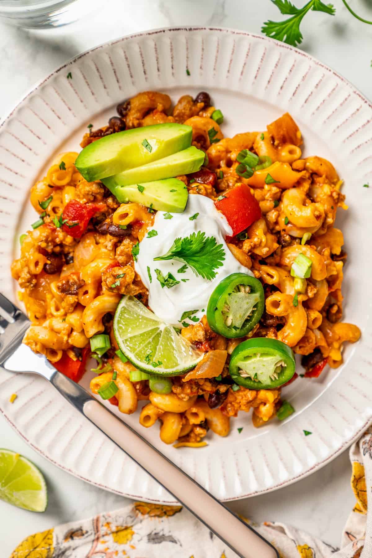 Close up of a plate with a serving of taco pasta with toppings.