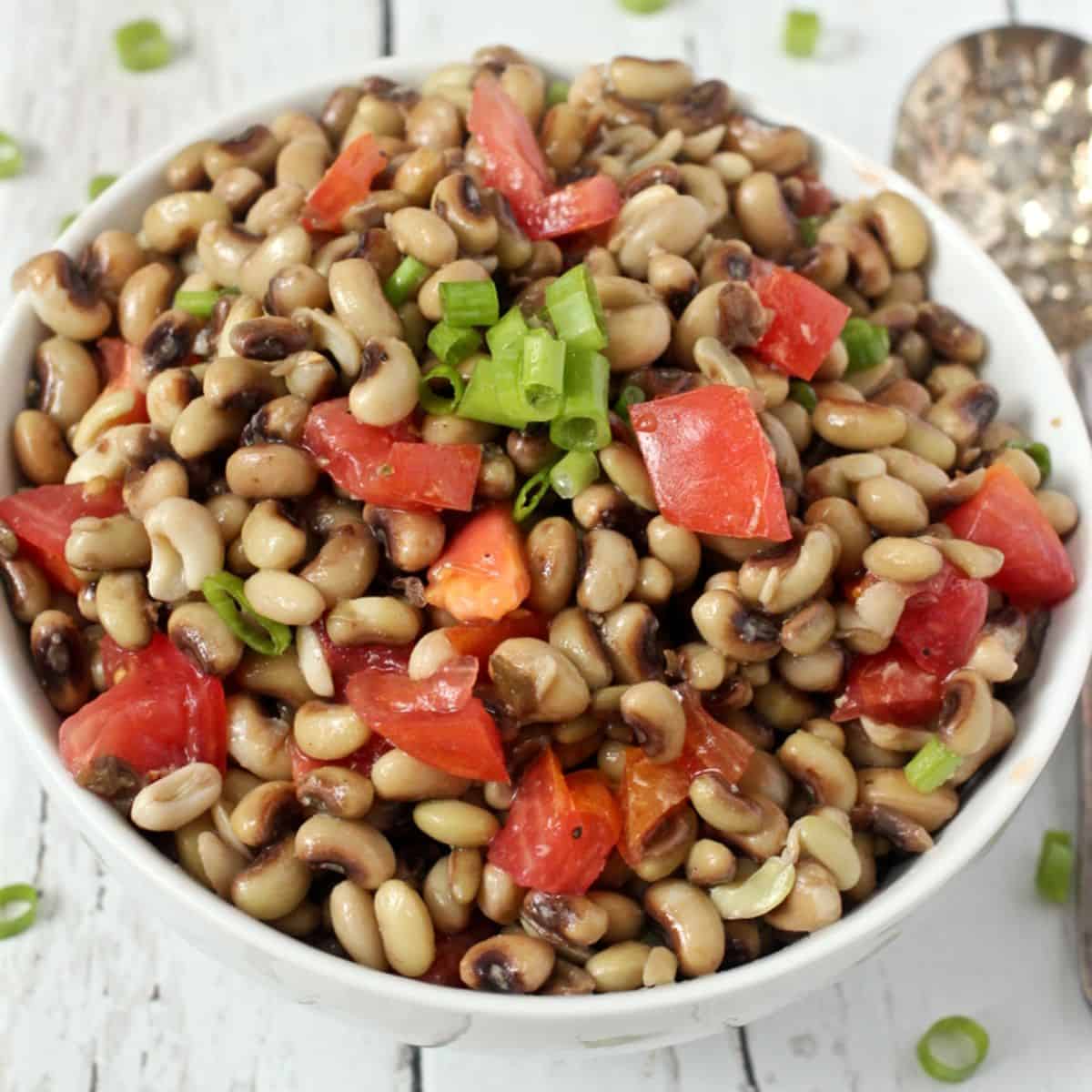 A white bowl full of a mixture of crowder peas with tomatoes and green onions.