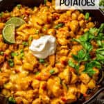 A cast iron skillet with a mixture of chicken and potatoes with cheese melted on top and a text overlay on the photo.