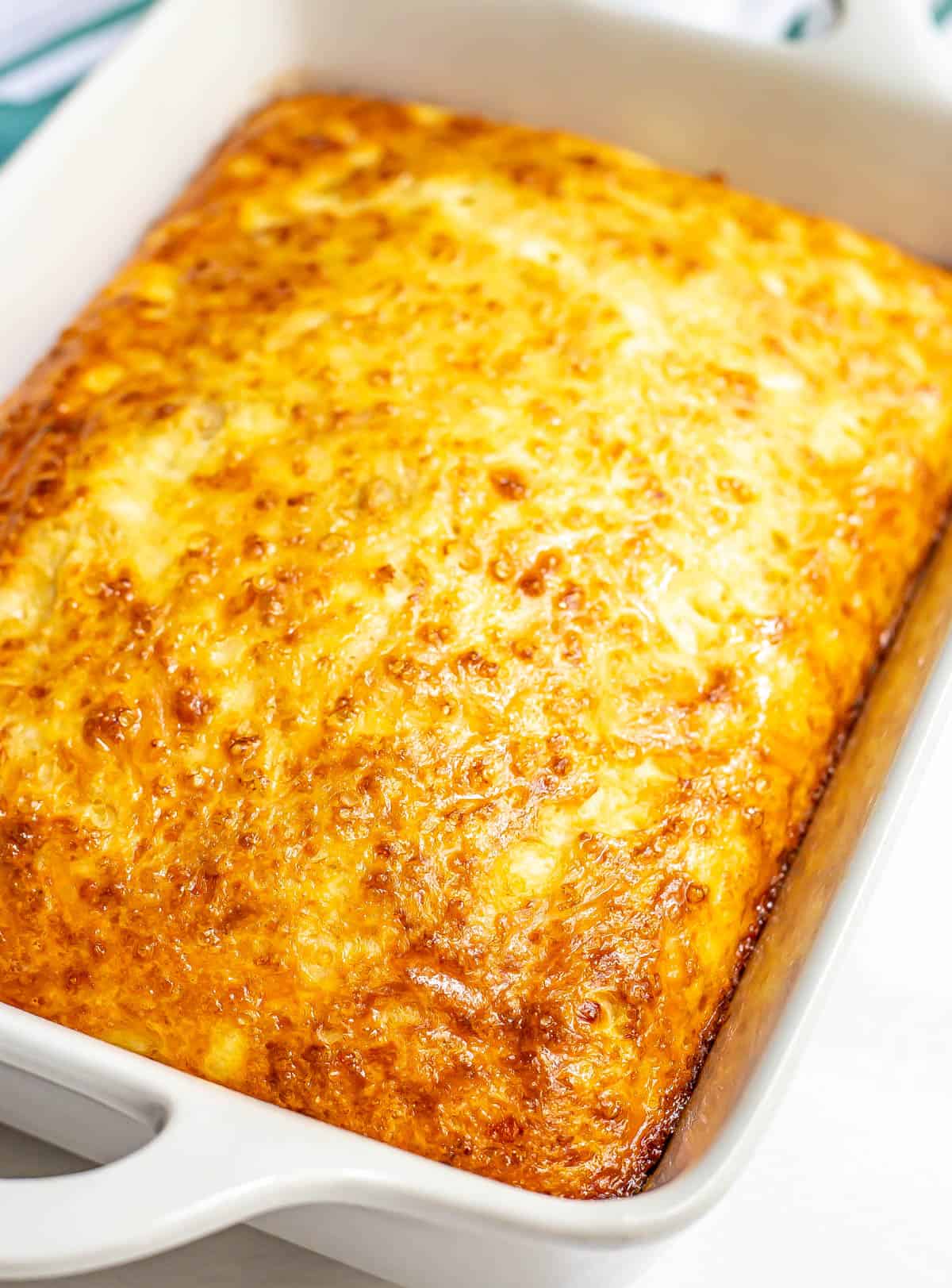 Side view of cheesy baked eggs in a large white rectangular casserole dish.