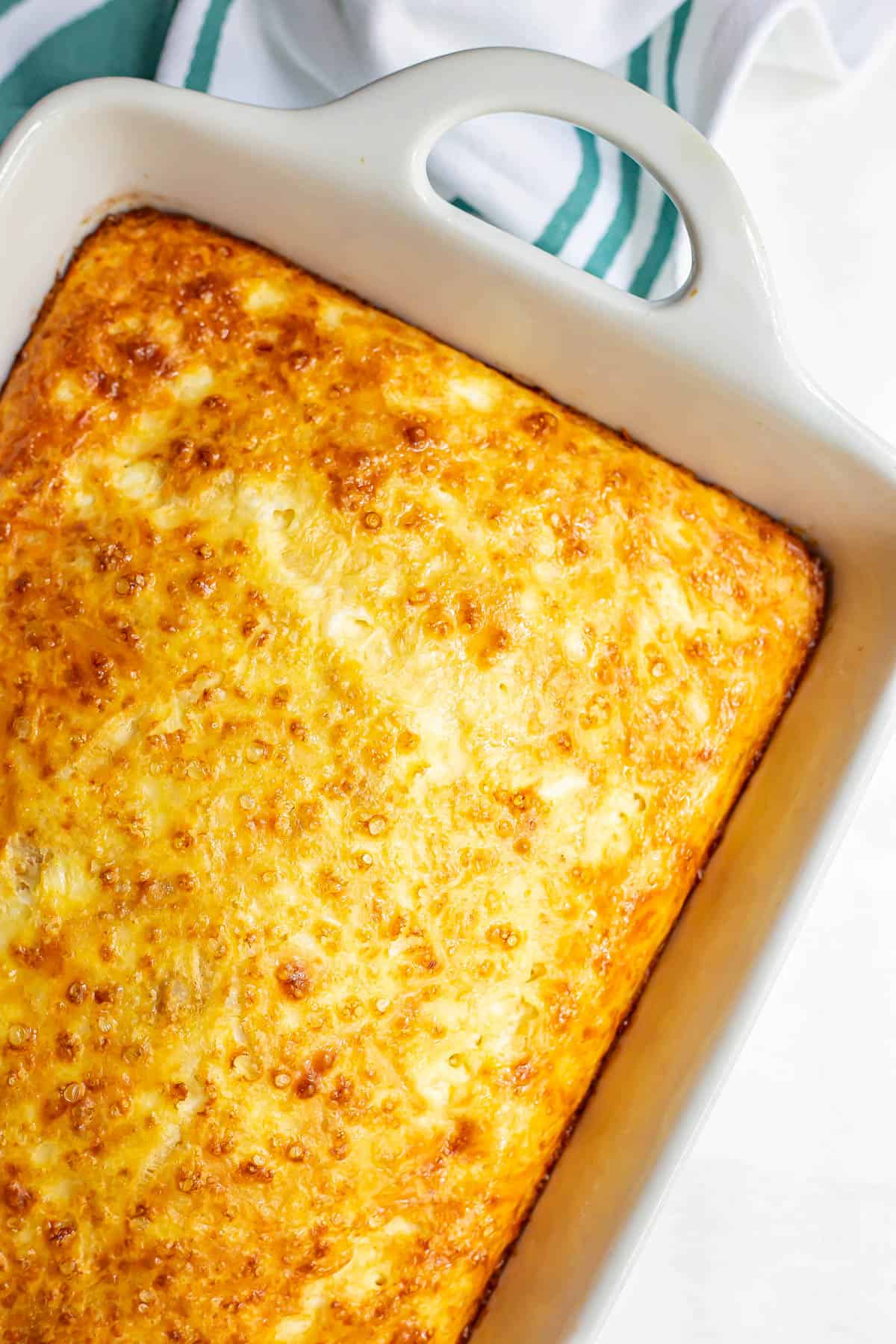 Cheesy baked eggs in a large white rectangular casserole dish.