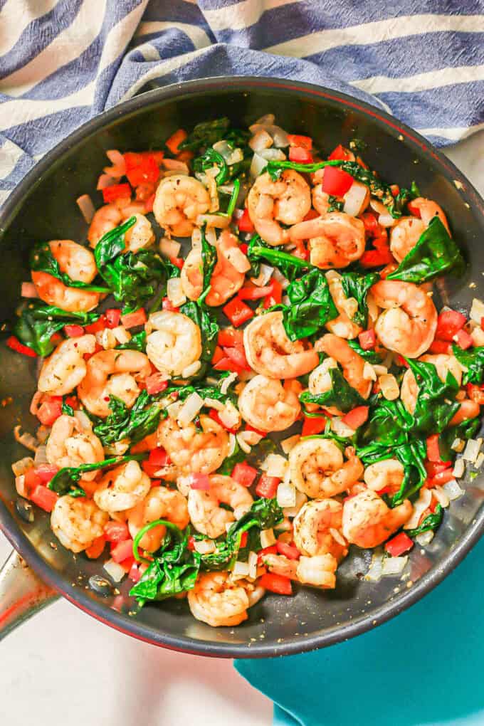 Shrimp, spinach and veggies all cooked together in a skillet.
