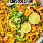 A spoon resting in a pan of a cheesy southwestern skillet chicken and rice dish with jalapenos, lime and avocado on top and a text overlay on the photo.