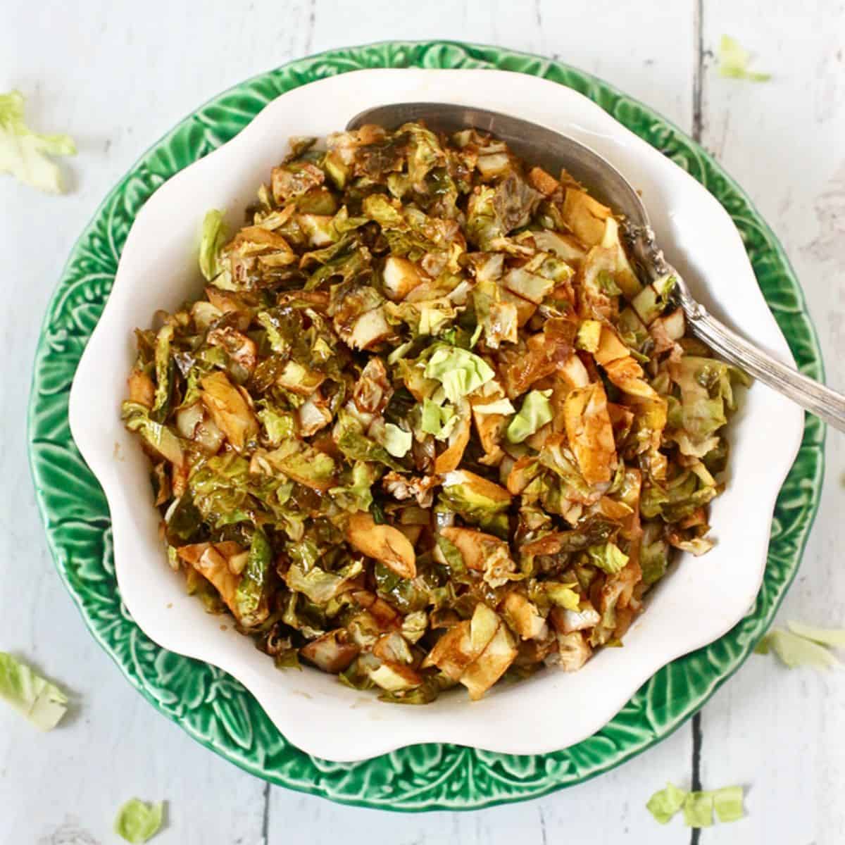 A bowl of cooked, shredded Brussels sprouts with a serving spoon resting in it.