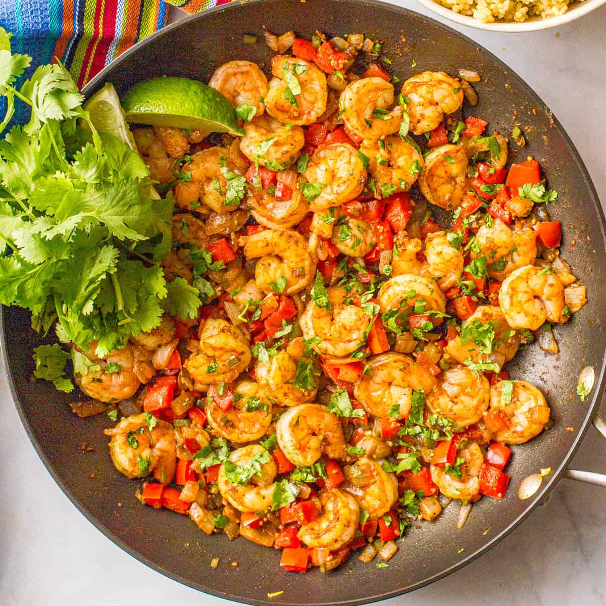 Close up of a skillet full of a Mexican shrimp and peppers saute with cilantro.