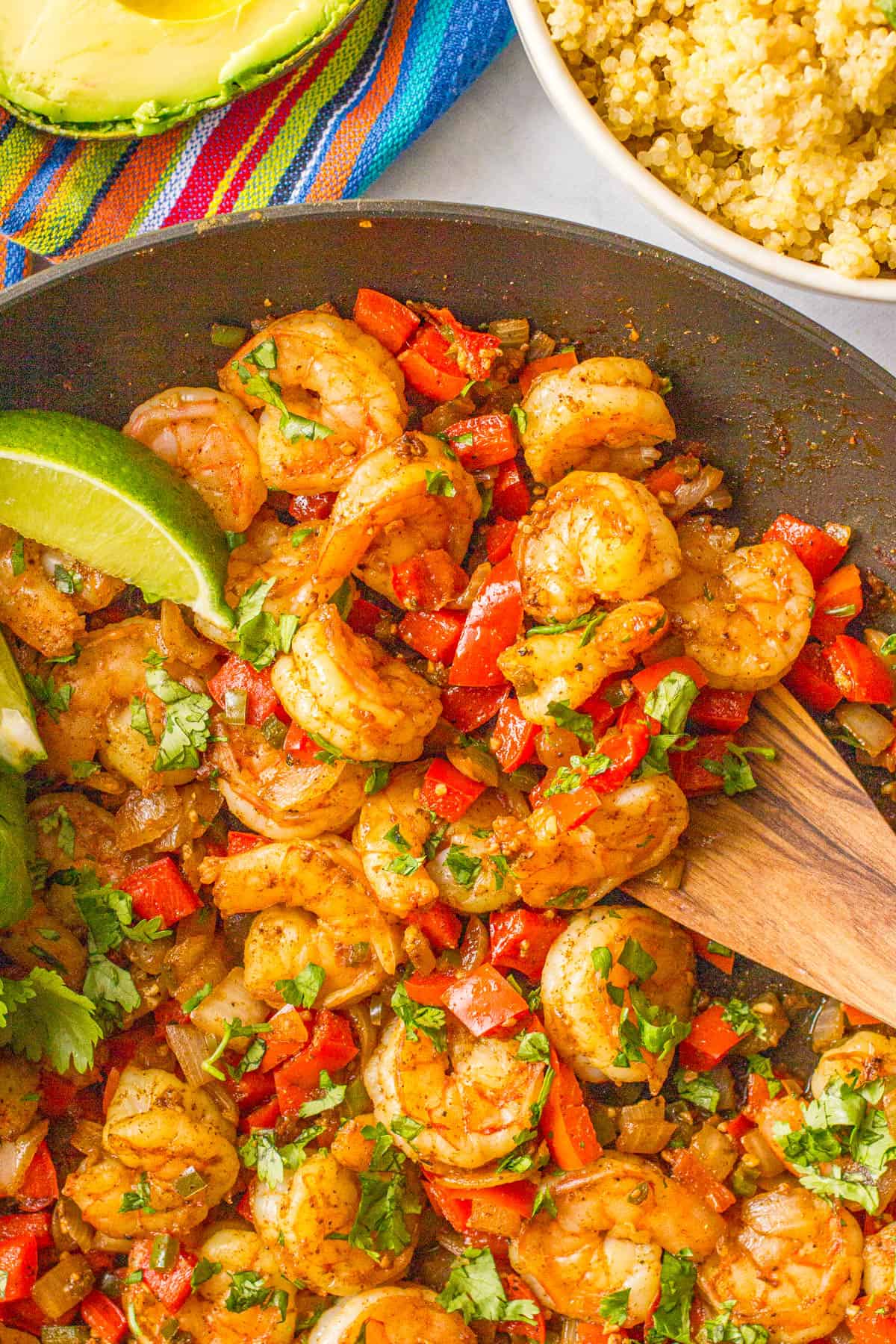 Close up of a scoop of a Mexican shrimp skillet being taken using a wooden spatula.