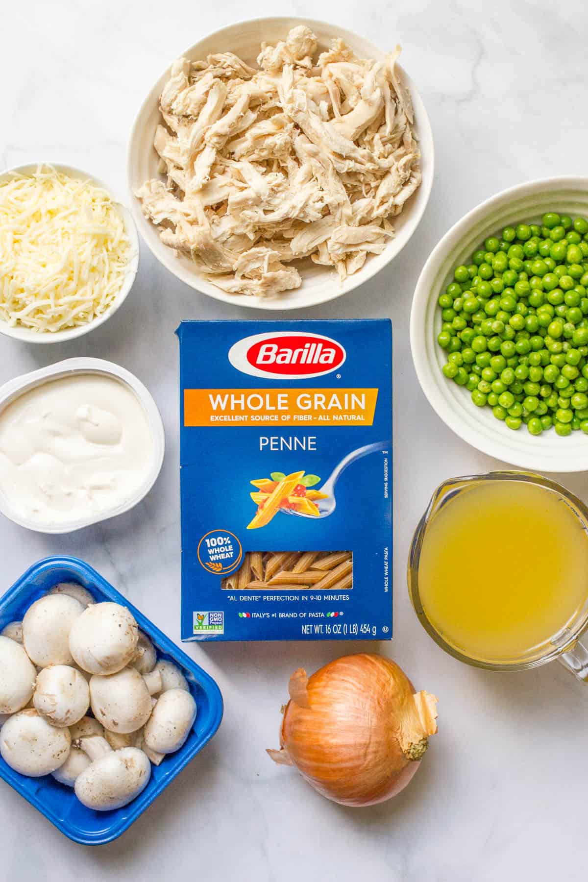 Ingredients laid out for making a chicken and mushroom pasta with peas.