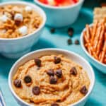 A small white bowl of chickpea cookie dough with chocolate chips on top and to the side and a text overlay on the photo.
