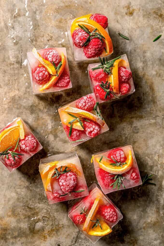 Frozen ice cubes with red berries and orange slices in them.