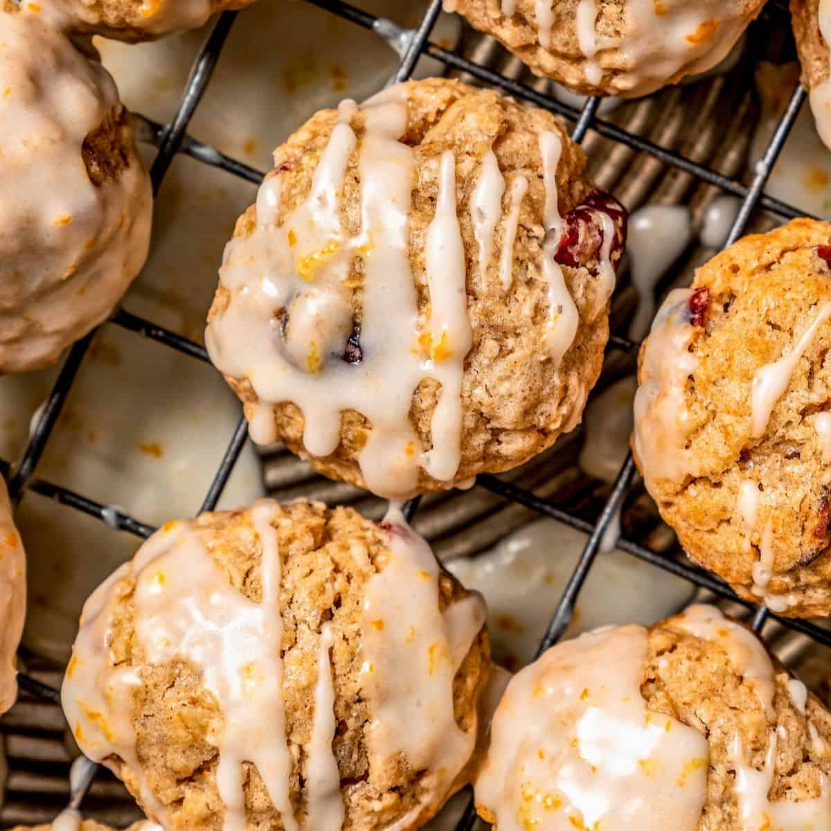 Close up of cranberry oatmeal cookies with a citrus drizzle on top on a cooling rack.