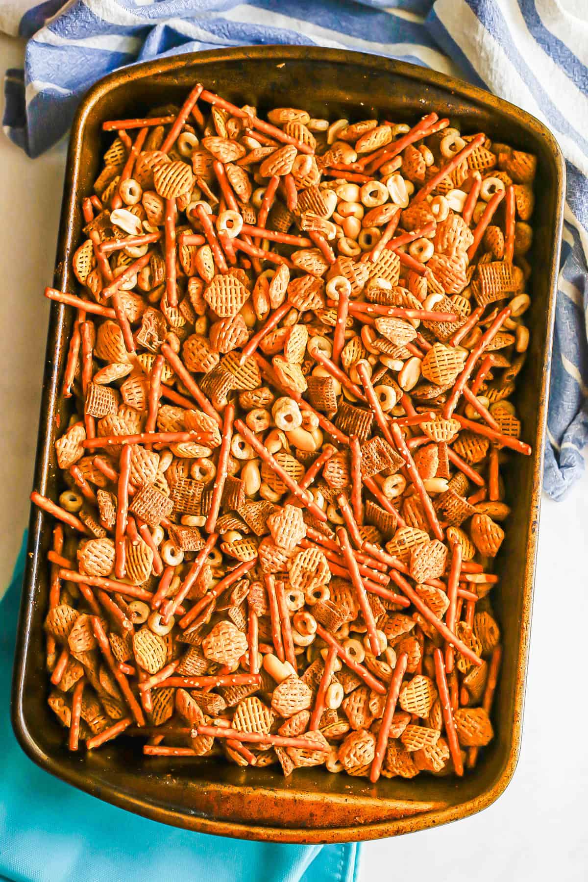Homemade chex mix in a baking pan after being baked in the oven.