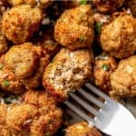 A meatball with a bite taken out on a fork that's resting in a platter of meatballs with a text overlay on the photo.