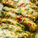 Cheesy pesto baked chicken strips in a casserole dish with a text overlay on the photo.