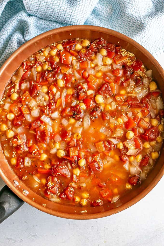 A copper skillet with a tomato and chickpeas mixture.