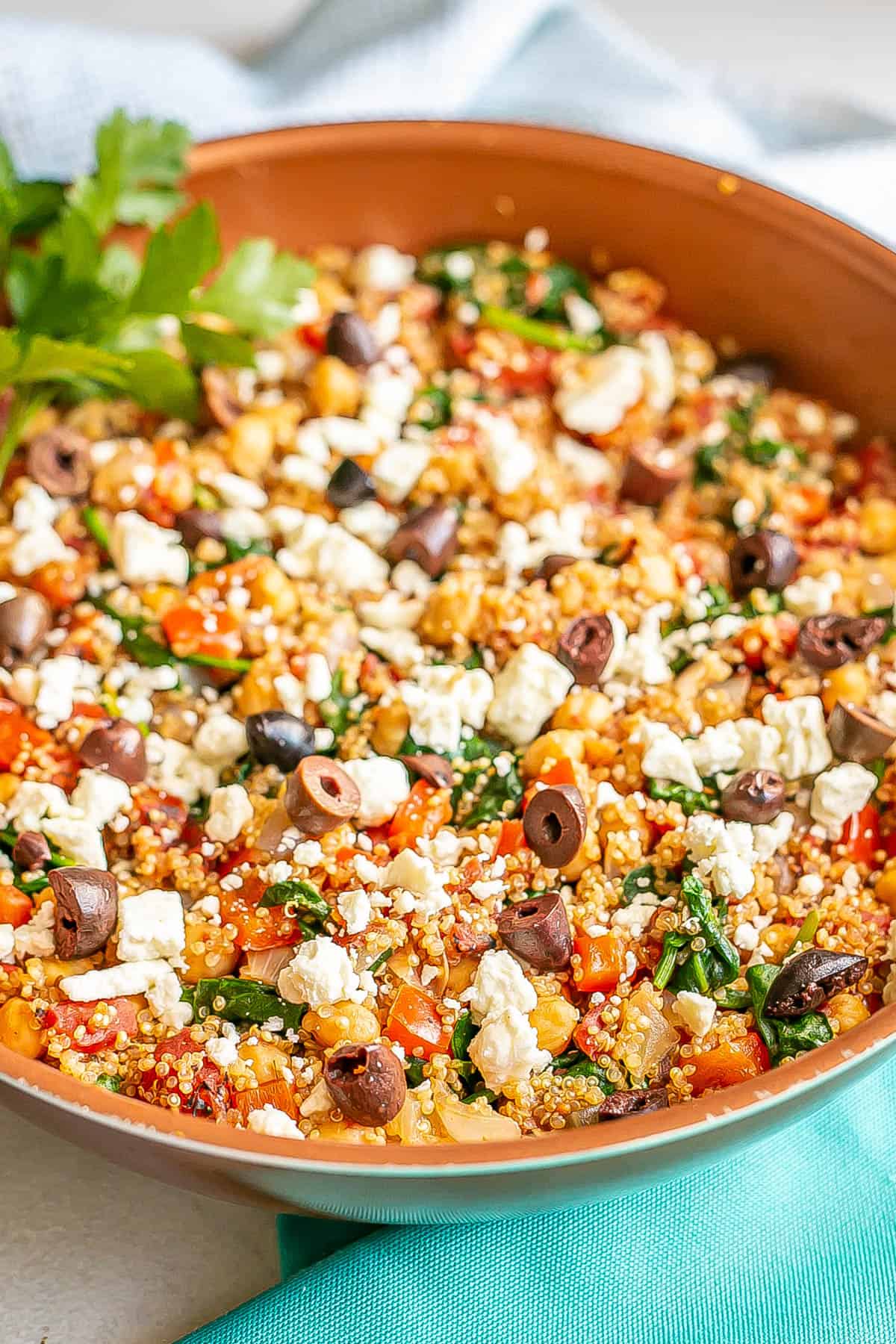 Mediterranean style quinoa with olives and feta cheese in a large copper skillet.