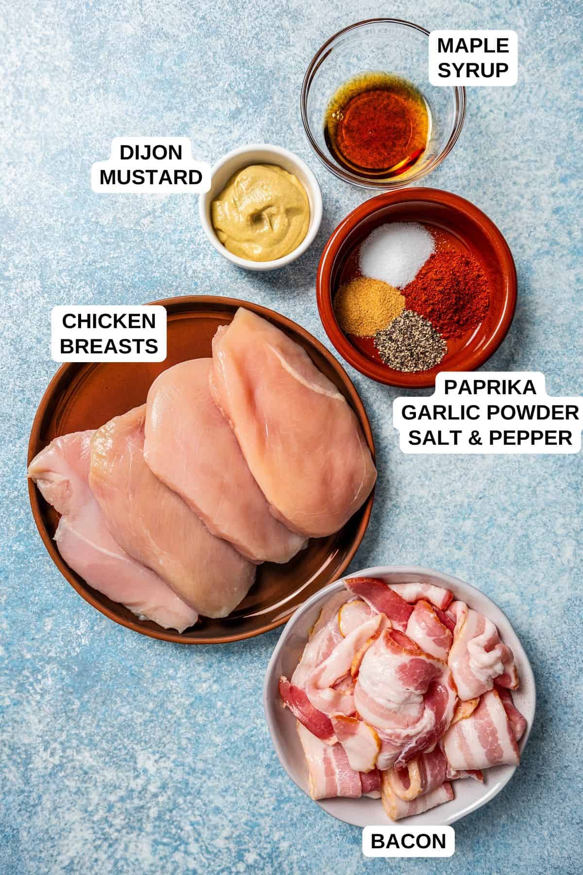 Chicken breasts, bacon, dijon mustard, maple syrup and seasonings laid out in different containers on a counter with labels for each one.