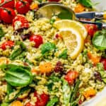 A bowl filled with a colorful orzo salad with tomatoes, spinach, feta and olives with a text box on top.