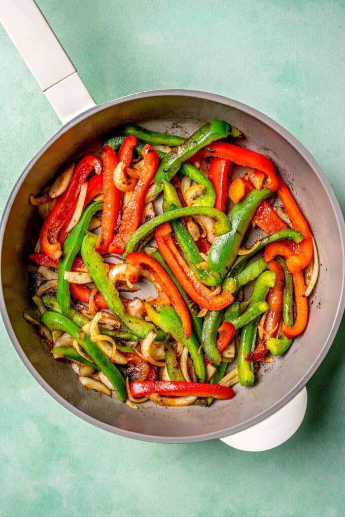 Sautéed onion and bell peppers in a skillet.