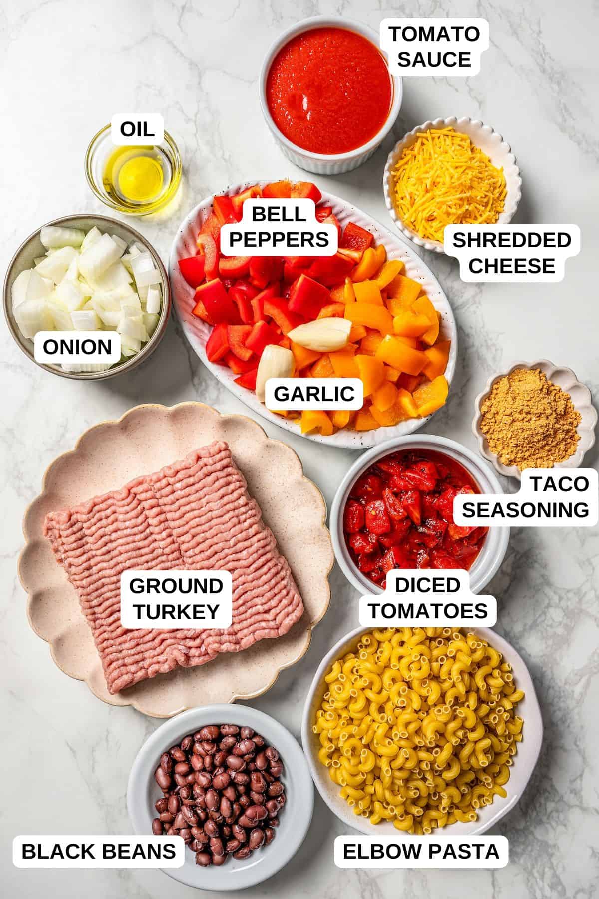 Ground turkey, beans, pasta, peppers and other ingredients laid out in separate bowls on a counter with labels for each one.