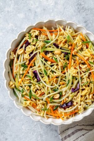 A bowl of a mixed coleslaw with ramen noodles and peanuts.