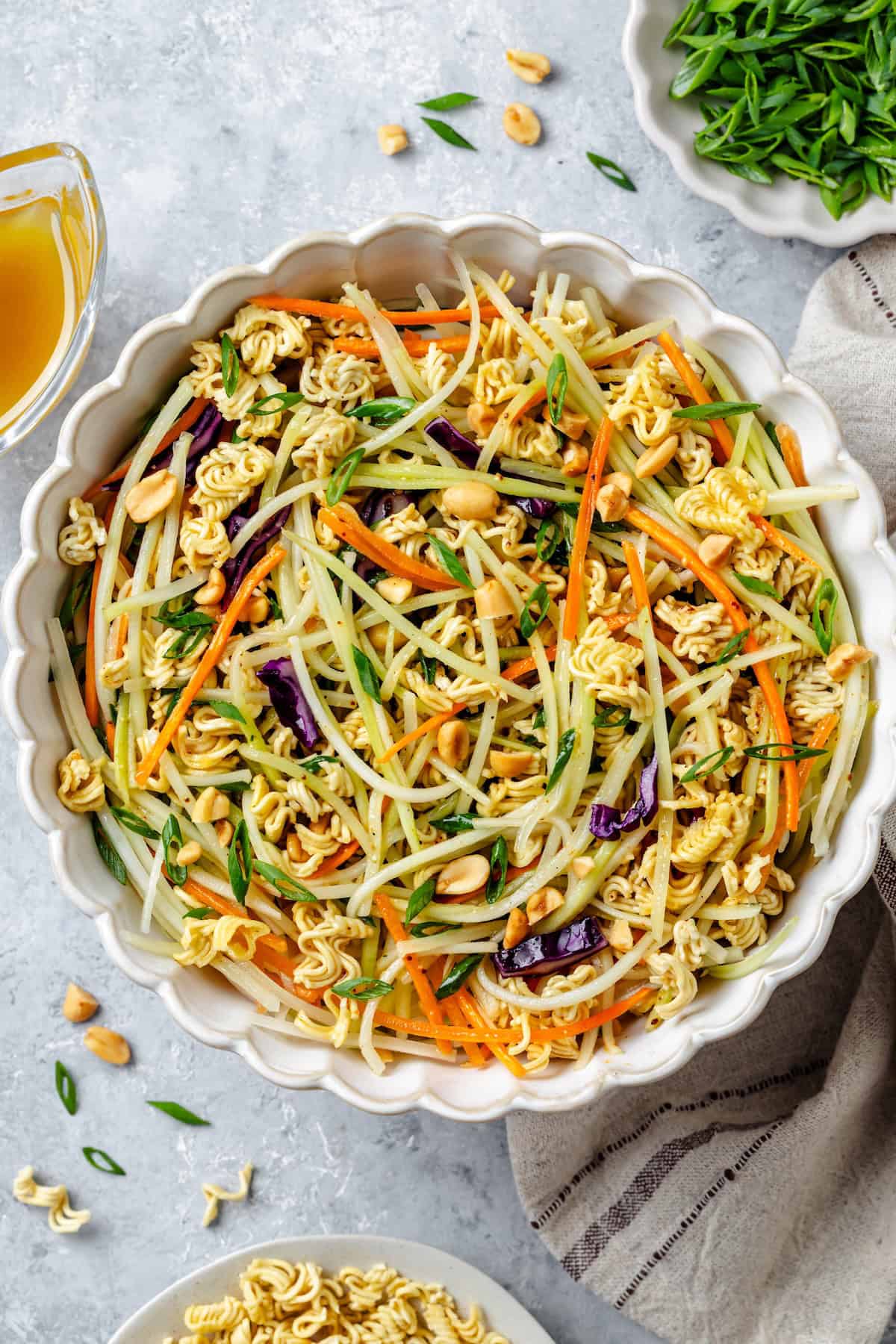 An Asian slaw with ramen noodles, peanuts and broccoli slaw in a large serving bowl.