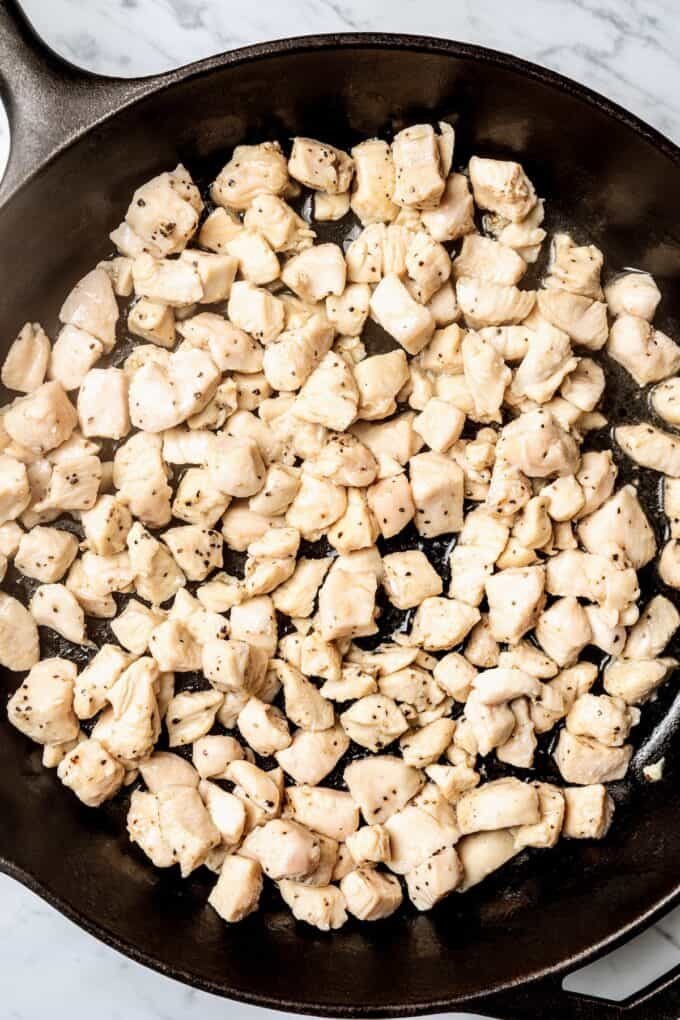 Cooked cubed chicken pieces in a cast iron skillet.