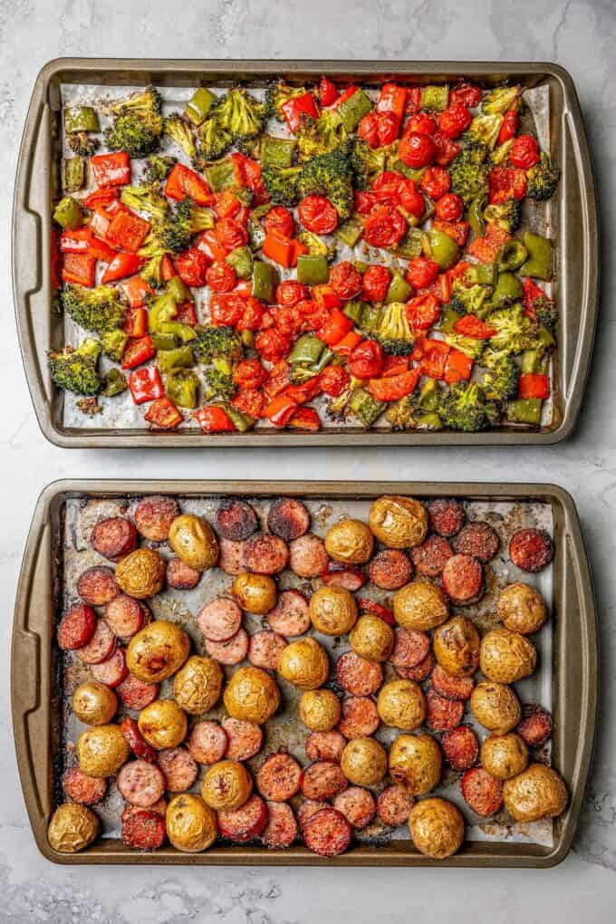 Two sheet pans, one with smoked sausage and baby potatoes, the other with peppers and broccoli, after roasting.