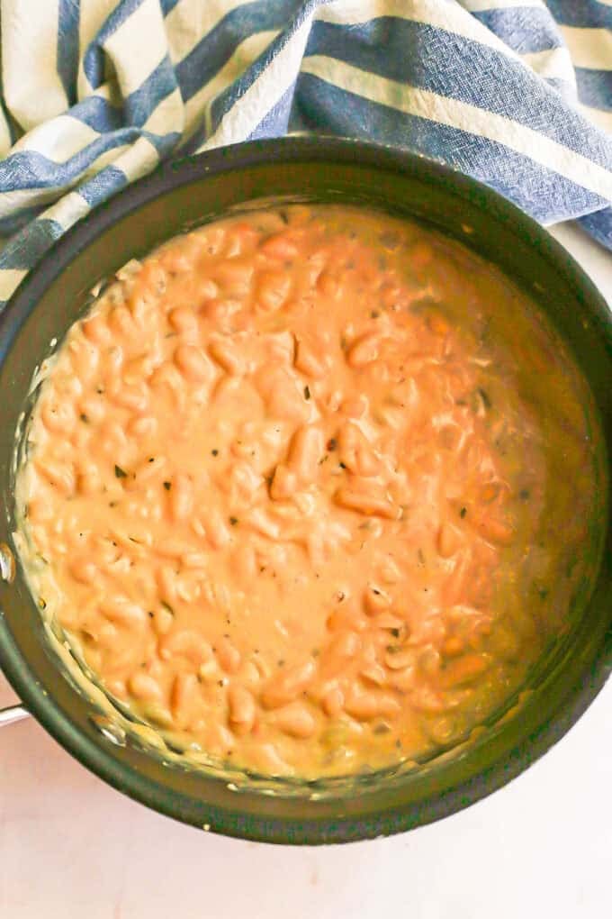 Creamy partially mashed white beans in a large pot.