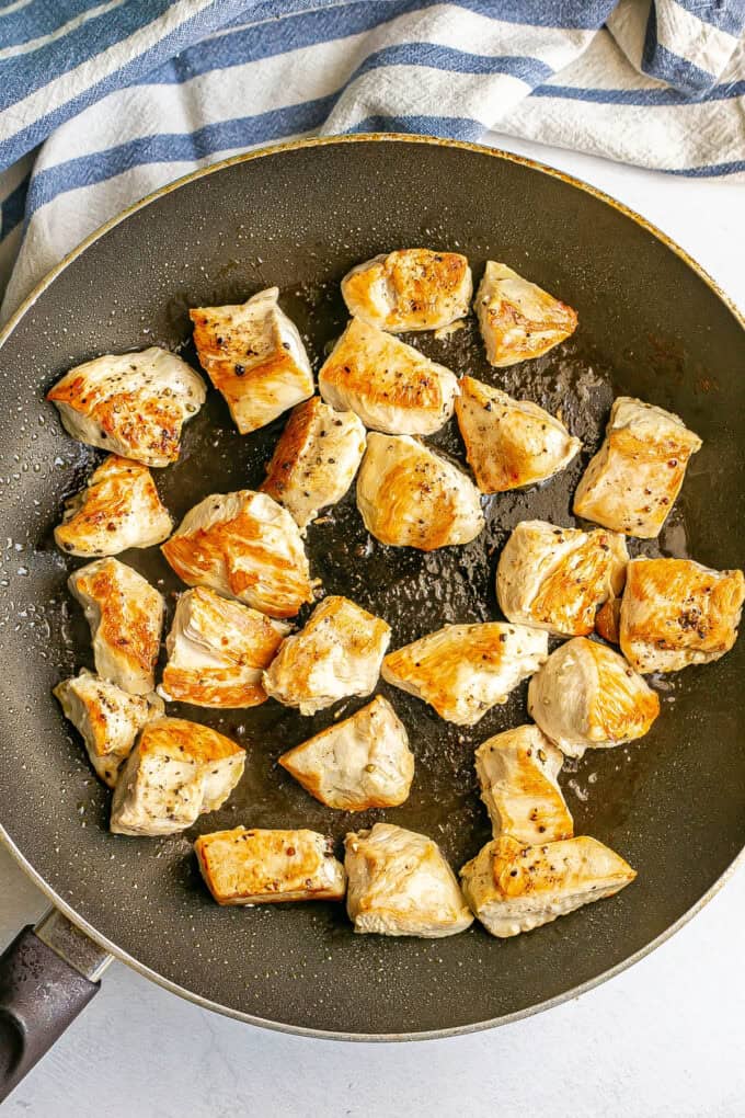 Seared cubed pieces of chicken in a large skillet.