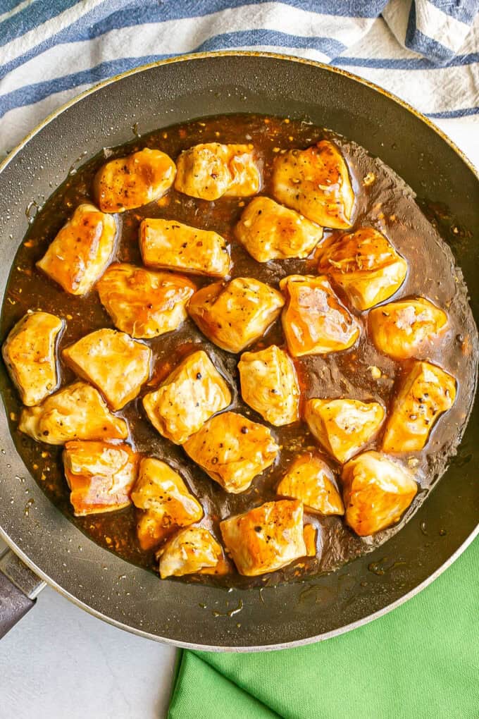 Seared cubed pieces of chicken in a teriyaki sauce in a large skillet.