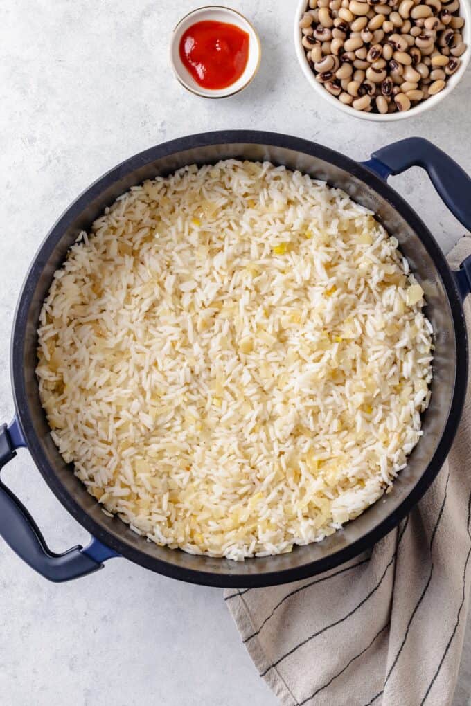 Cooked rice with sautéed onions in a dark pot.