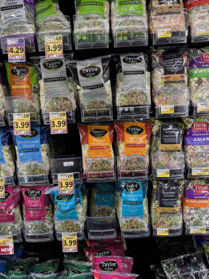 Bagged salad kits in a grocery store case.