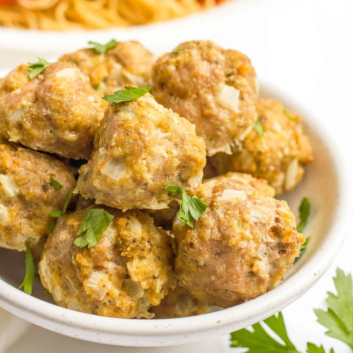 Close up of a bowl of homemade turkey meatballs with parsley sprinkled over top.