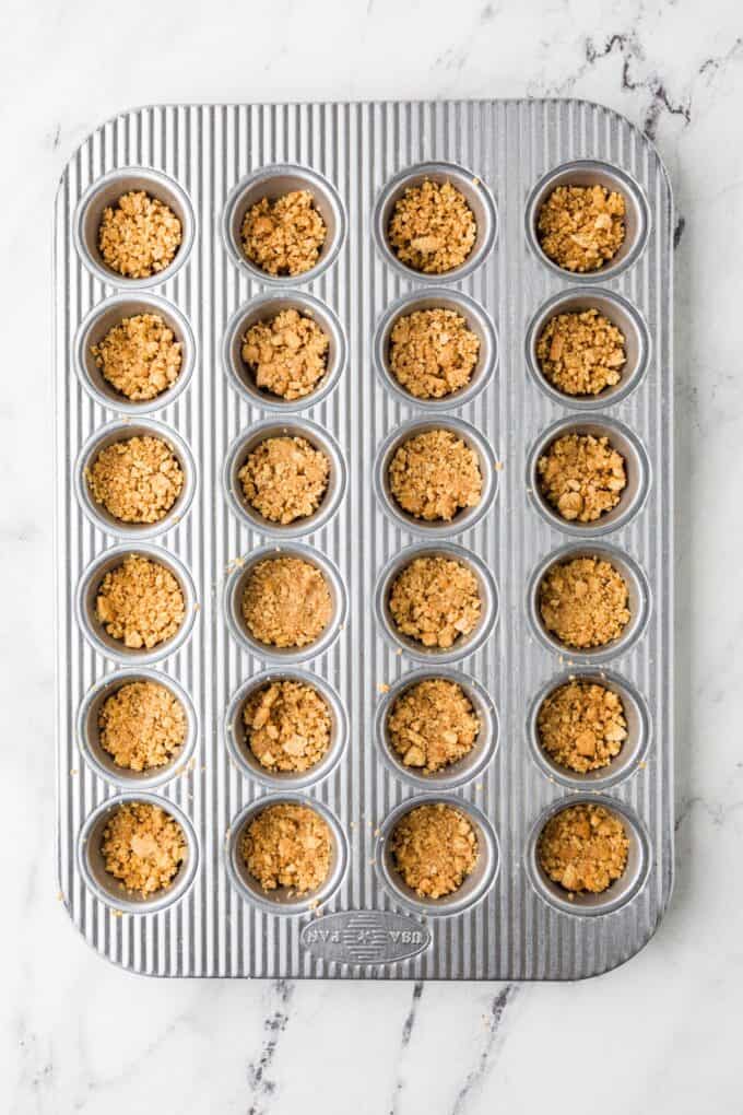 A mini muffin tin with a graham cracker mixture pressed into the bottoms as a base.